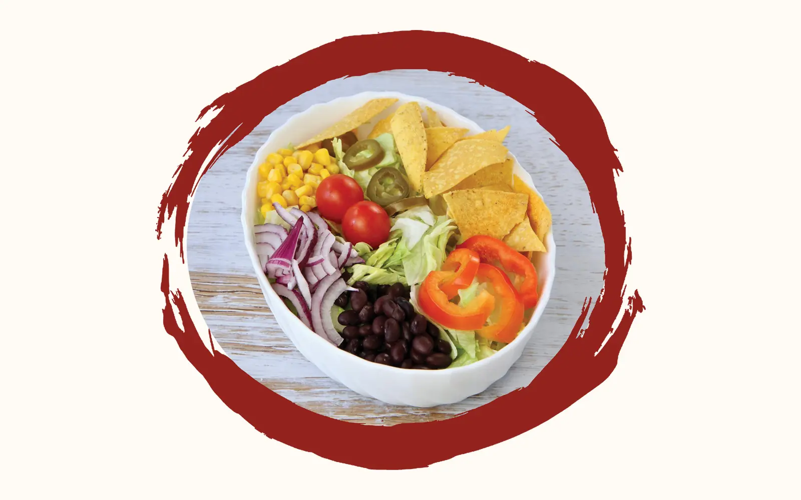 Weisse Schale mit Eisbergsalat, schwarzen Bohnen, Mais, roten Zwiebeln, Kirschtomaten, Paprikaringen, Jalapeños und Tortillachips auf hellem Holztisch